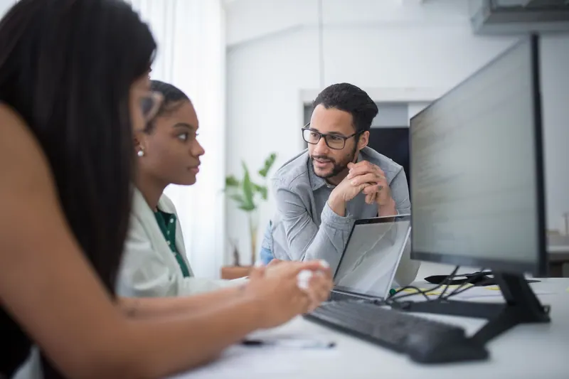 Entwickler arbeiten an Laptops in einem Teambüro an einem Softwareprojekt